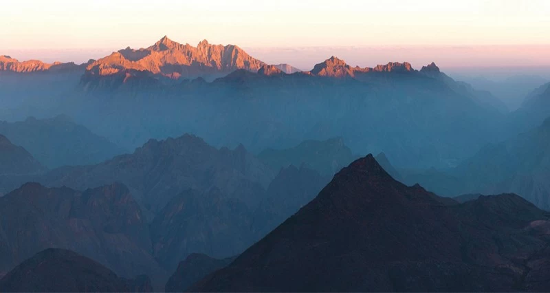 أشعة الشمس تنثر خيوطها بالجمال على المرتفعات الجبلية المطلة على ولاية الرستاق