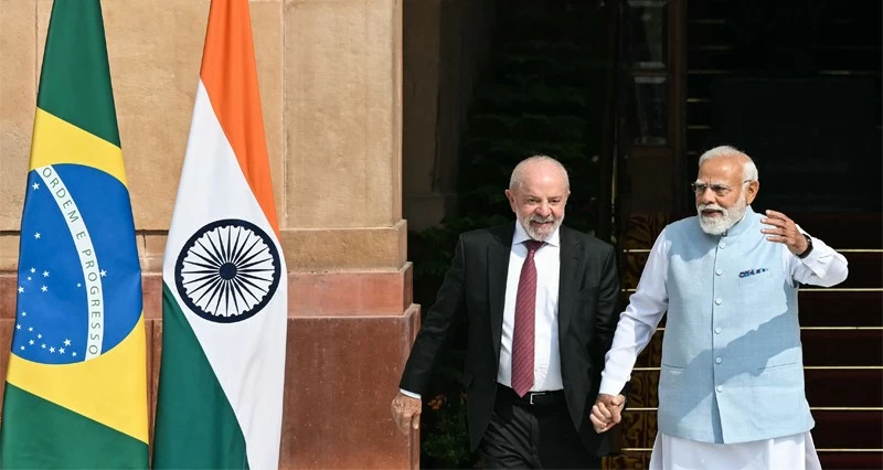 رئيس الوزراء الهندي ناريندرا مودي يمسك بيد الرئيس البرازيلي لويس إيناسيو لولا دا سيلفا أثناء سيرهما قبل اجتماعهما في نيودلهي.