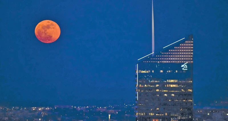 القمر الدموي يظهر فوق أحد المباني الشاهقة بمدينة ليون الفرنسية