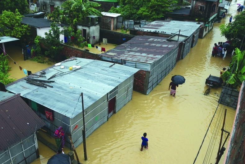هنود يشقون طريقهم عبر مياه الفيضانات من نهر بانتشاناي في سيليجوري بالهند بسبب هطول الأمطار