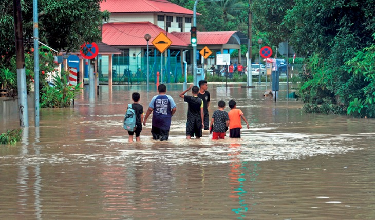 ماليزيون يشقون طريقهم من خلال شوارع غمرتها المياه بعد هطول الأمطار الغزيرة