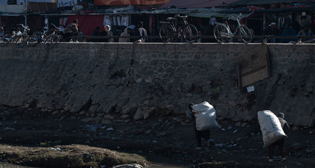 رجال يبحثون عن مواد قابلة لإعادة التدوير على طول ضفاف نهر كابول